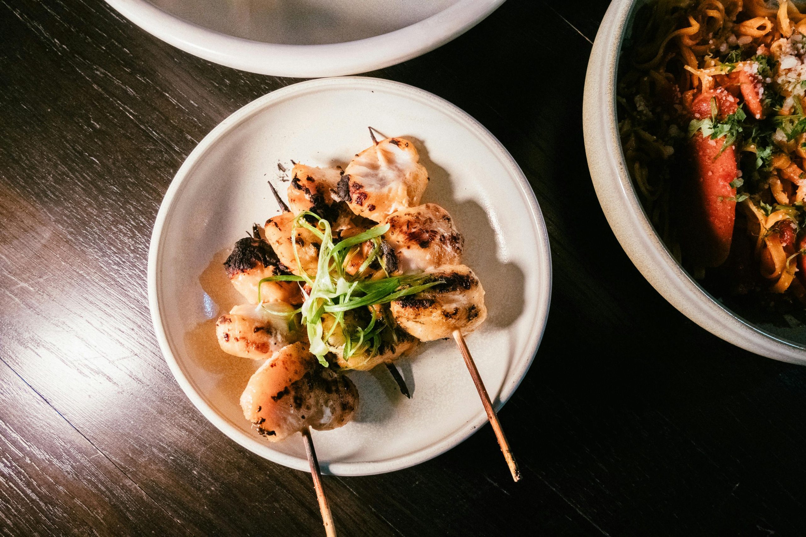 Delicious grilled chicken skewers garnished with fresh scallions, served on a stylish plate.